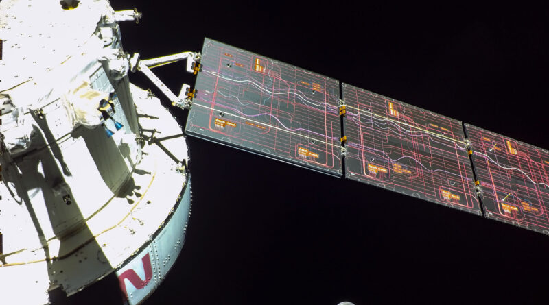 Photo of the Orion capsule, a white spacecraft with a solar array deployed, with the moon in the background.