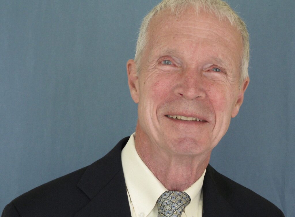 an old man in a suit and tie looking into the camera